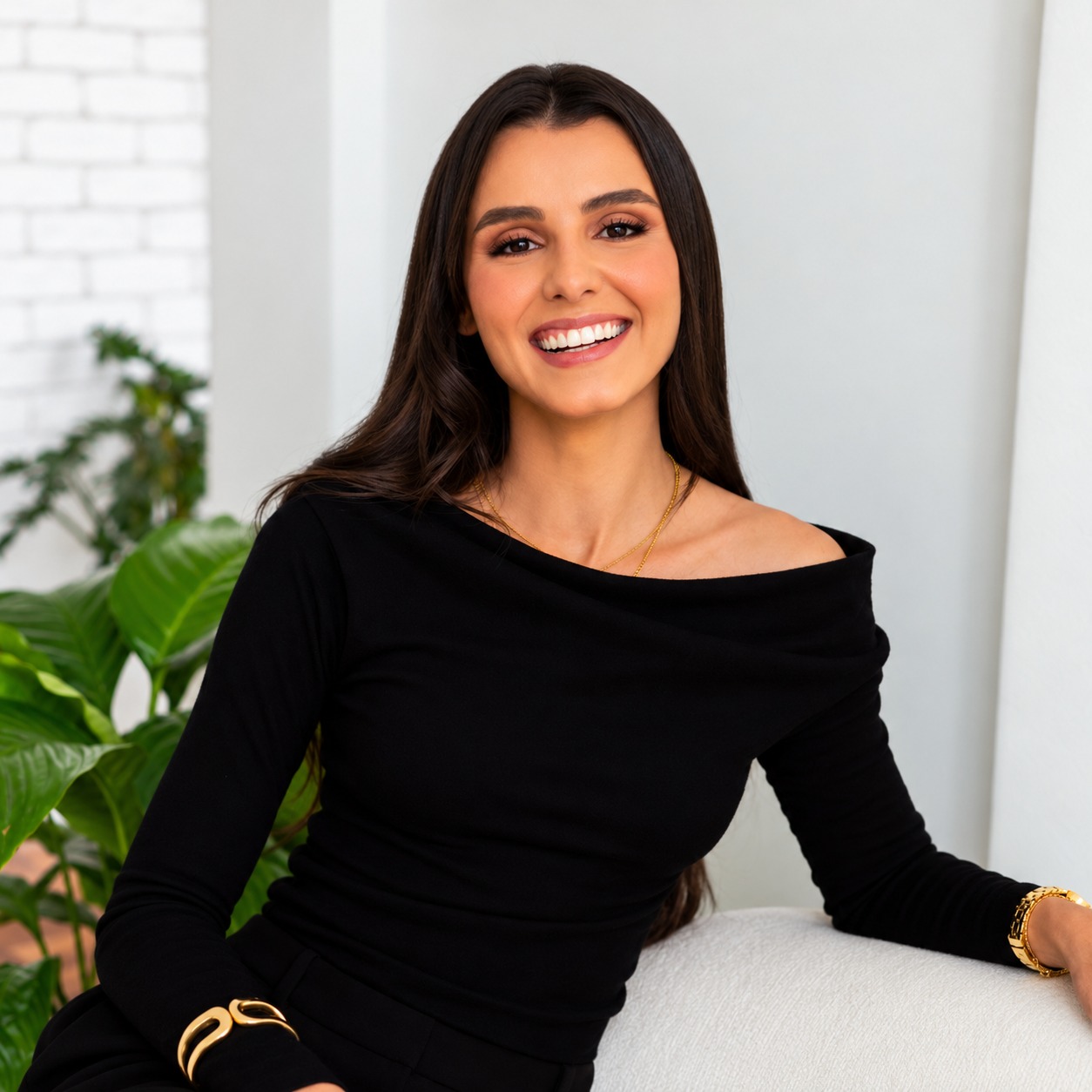 Ana Jaqueline sorrindo, sentada em um sofá claro